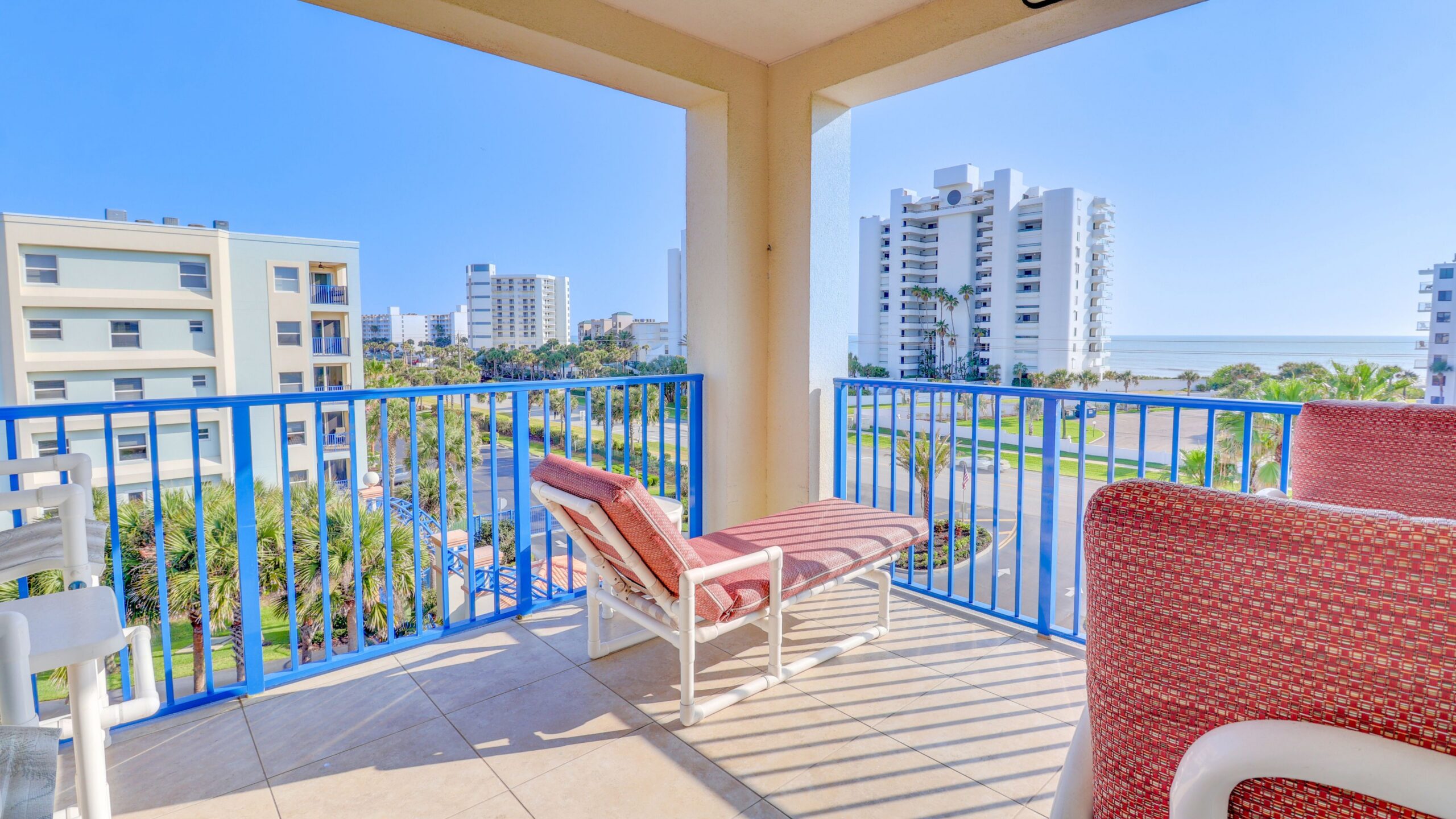 Ocean-view balcony at an Oceanwalk condo in New Smyrna Beach with blue railings and lounge seating