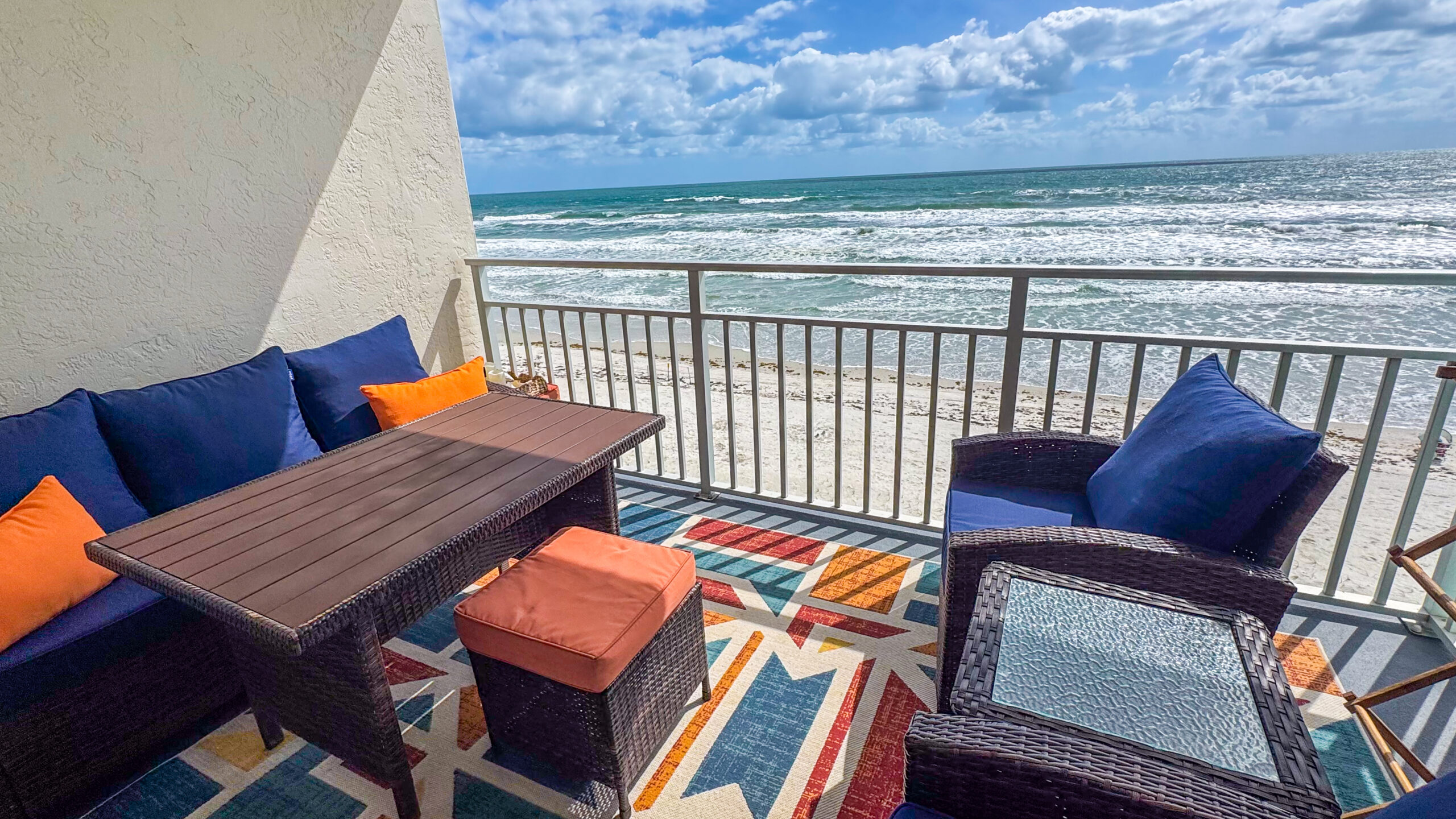Oceanfront balcony at Sea Coast Gardens II 303 with blue and orange seating overlooking New Smyrna Beach